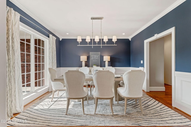 dining space with hardwood / wood-style floors, crown molding, and a chandelier