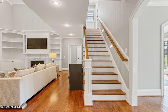 stairs with crown molding, a towering ceiling, and wood-type flooring