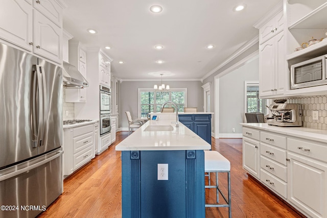 kitchen featuring blue cabinets, white cabinetry, sink, stainless steel appliances, and a center island with sink