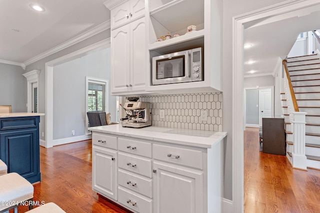 kitchen with appliances with stainless steel finishes, a breakfast bar area, white cabinets, and wall chimney exhaust hood