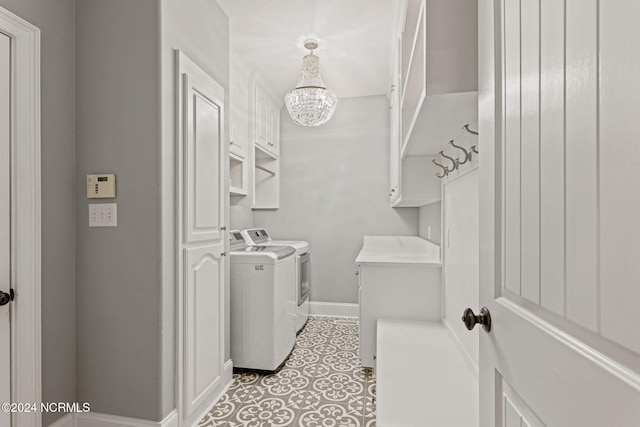 laundry room with cabinets, light tile patterned flooring, washing machine and clothes dryer, and a chandelier