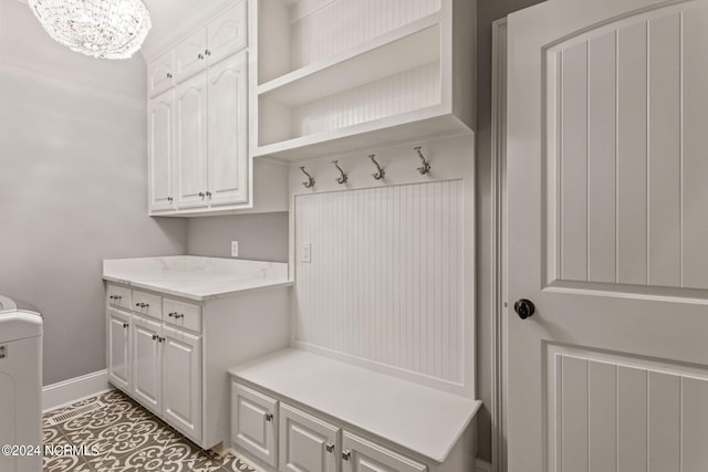 mudroom with washer / dryer, dark tile patterned flooring, and a notable chandelier