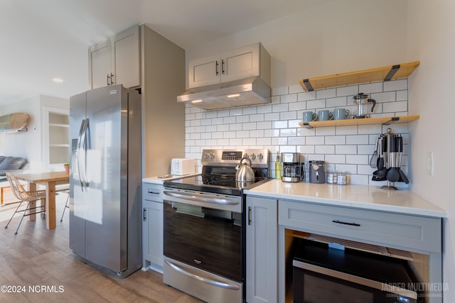 kitchen with light hardwood / wood-style floors, white cabinetry, stainless steel appliances, and backsplash