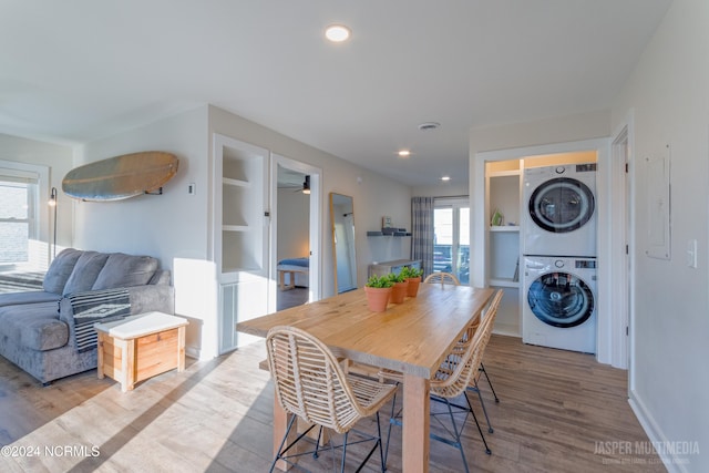 dining area with light wood-type flooring, stacked washer and clothes dryer, and ceiling fan