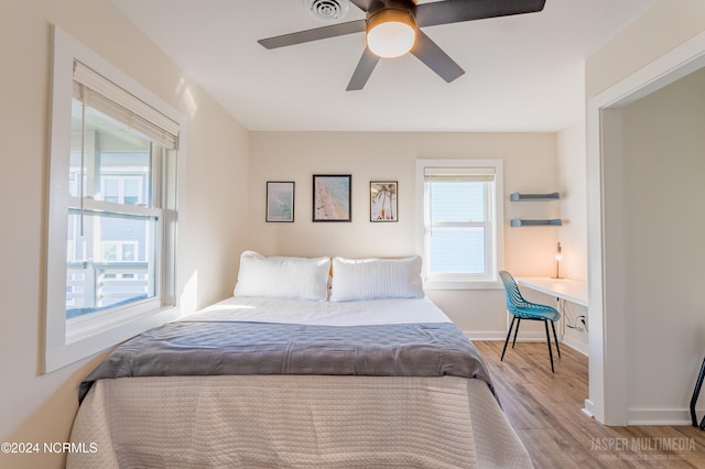 bedroom with light hardwood / wood-style floors, built in desk, and ceiling fan