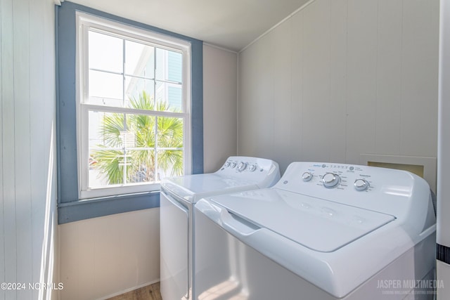 laundry area featuring hardwood / wood-style floors, wooden walls, and washer and dryer