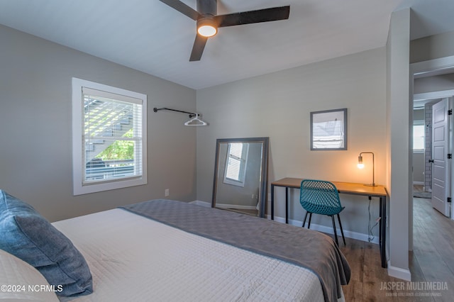 bedroom with built in desk, dark wood-type flooring, and ceiling fan