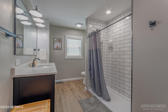 bathroom with toilet, hardwood / wood-style floors, curtained shower, and vanity