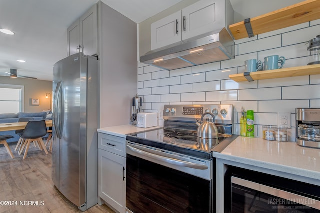 kitchen featuring appliances with stainless steel finishes, white cabinetry, tasteful backsplash, and light wood-type flooring