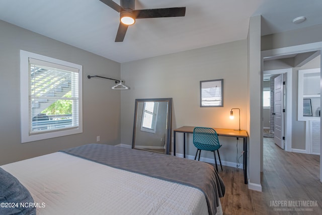 bedroom with built in desk, ceiling fan, and hardwood / wood-style flooring