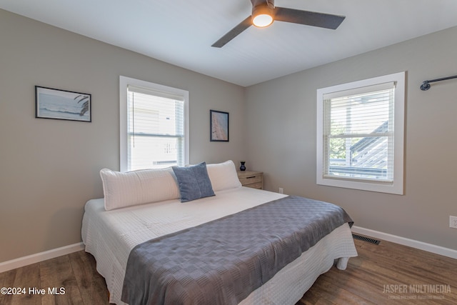 bedroom with ceiling fan, multiple windows, and dark hardwood / wood-style flooring