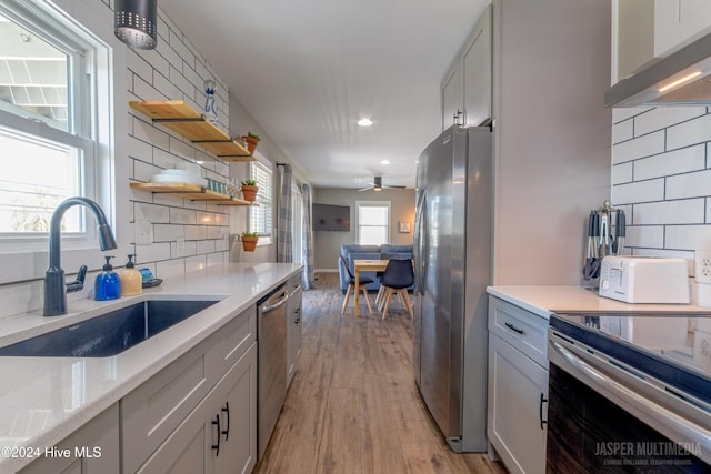 kitchen with decorative backsplash, light hardwood / wood-style flooring, stainless steel appliances, a healthy amount of sunlight, and sink