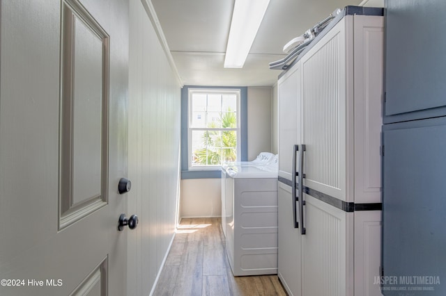 clothes washing area with cabinets, light wood-type flooring, and washing machine and clothes dryer