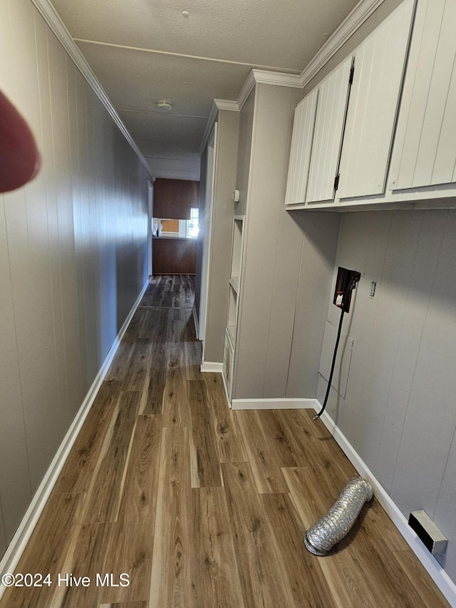 clothes washing area featuring dark wood-type flooring, wood walls, cabinets, ornamental molding, and hookup for a washing machine