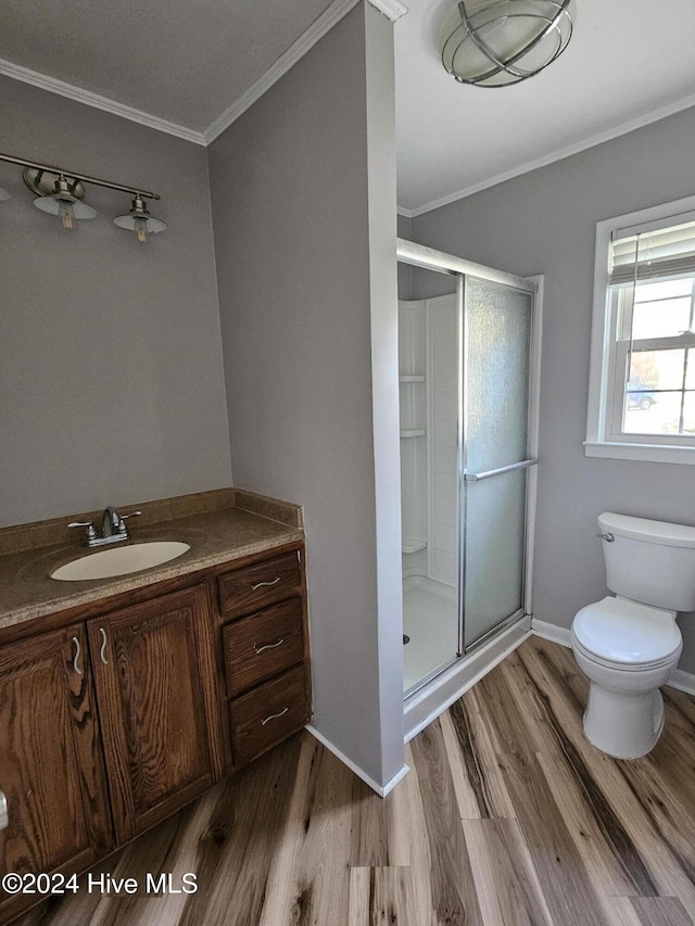 bathroom featuring toilet, crown molding, vanity, a shower with door, and hardwood / wood-style floors