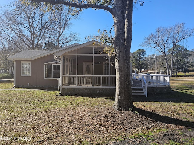 rear view of house with a sunroom, a yard, and a deck