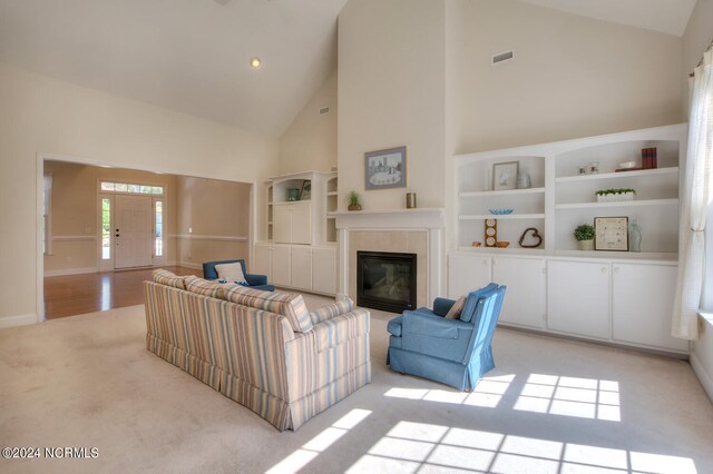 carpeted living room featuring a tiled fireplace and high vaulted ceiling