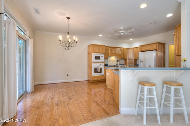 kitchen with decorative light fixtures, ceiling fan with notable chandelier, light wood-type flooring, and white appliances