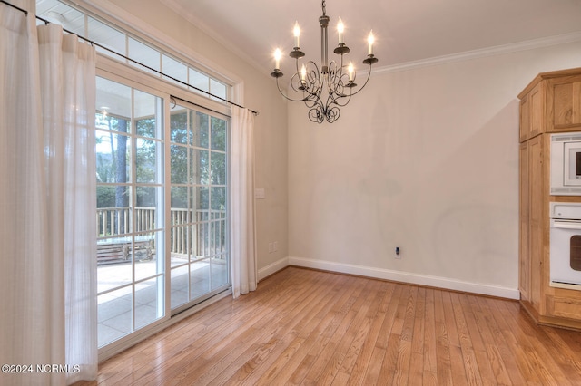 unfurnished dining area with light hardwood / wood-style floors, crown molding, and an inviting chandelier