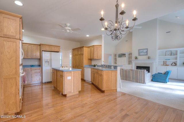 kitchen with white appliances, a center island, kitchen peninsula, hanging light fixtures, and light hardwood / wood-style flooring