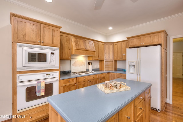 kitchen featuring a center island, light hardwood / wood-style flooring, crown molding, and white appliances