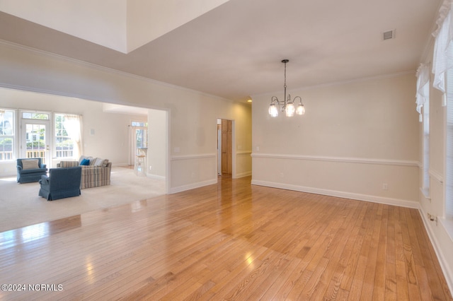 spare room with ornamental molding, light hardwood / wood-style flooring, and a notable chandelier