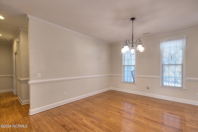 spare room with light hardwood / wood-style floors, crown molding, and an inviting chandelier