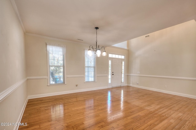 empty room featuring crown molding, a chandelier, and light wood-type flooring