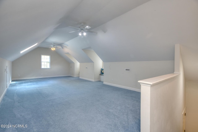 bonus room with lofted ceiling with skylight, carpet flooring, and ceiling fan