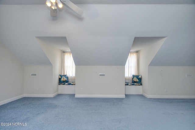 additional living space featuring vaulted ceiling, light carpet, and a healthy amount of sunlight