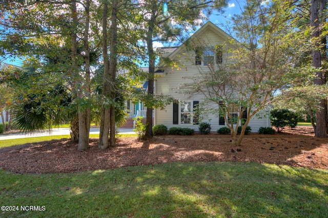 view of property hidden behind natural elements featuring a front yard