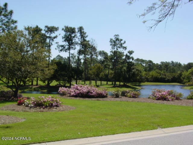 surrounding community featuring a water view and a lawn