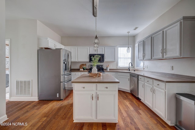 kitchen with black appliances, a kitchen island, dark hardwood / wood-style floors, and hanging light fixtures