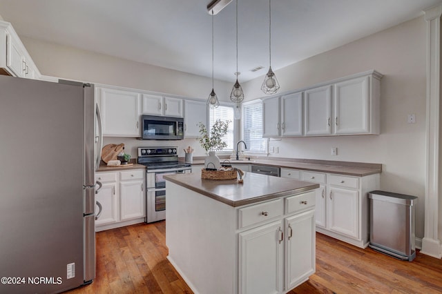 kitchen featuring white cabinets, stainless steel appliances, pendant lighting, light hardwood / wood-style floors, and a center island