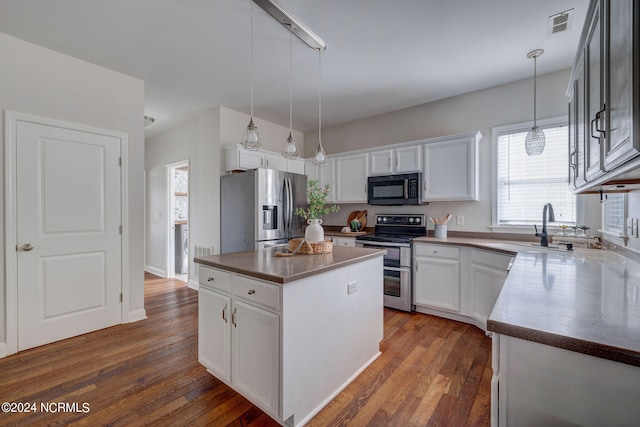 kitchen featuring hanging light fixtures, a center island, white cabinetry, appliances with stainless steel finishes, and dark hardwood / wood-style flooring