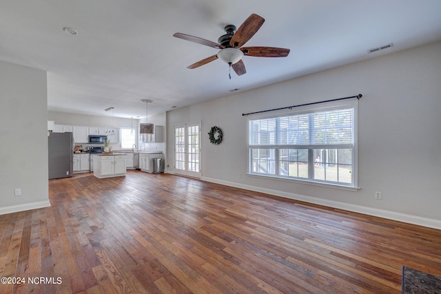 unfurnished living room featuring a healthy amount of sunlight, ceiling fan, and dark hardwood / wood-style flooring