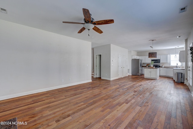 unfurnished living room featuring light hardwood / wood-style floors, sink, and ceiling fan