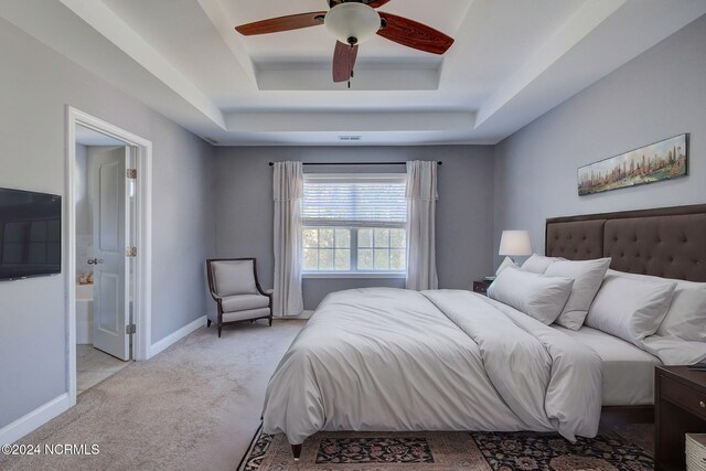 bedroom with ceiling fan, light carpet, and a raised ceiling