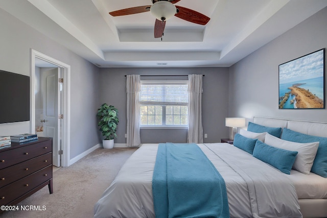 bedroom featuring ceiling fan, a tray ceiling, and light colored carpet