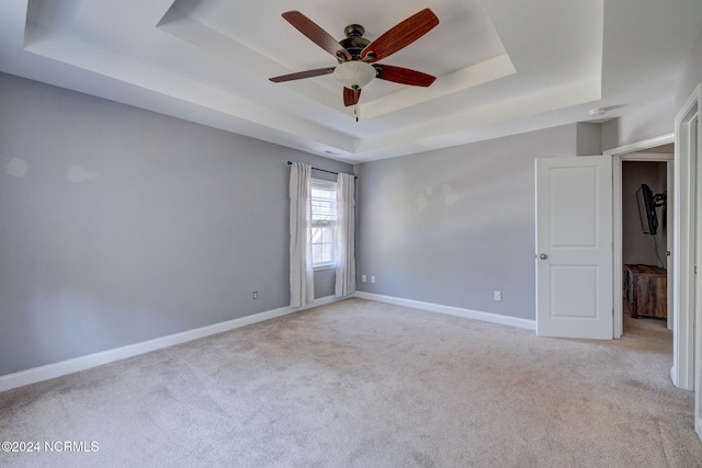 carpeted empty room featuring ceiling fan and a tray ceiling