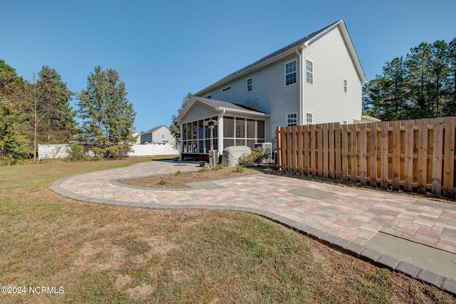 back of property featuring a yard, a sunroom, and a patio