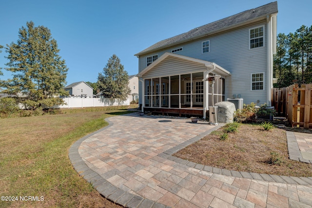 rear view of house featuring a yard, a patio, central AC unit, and a sunroom