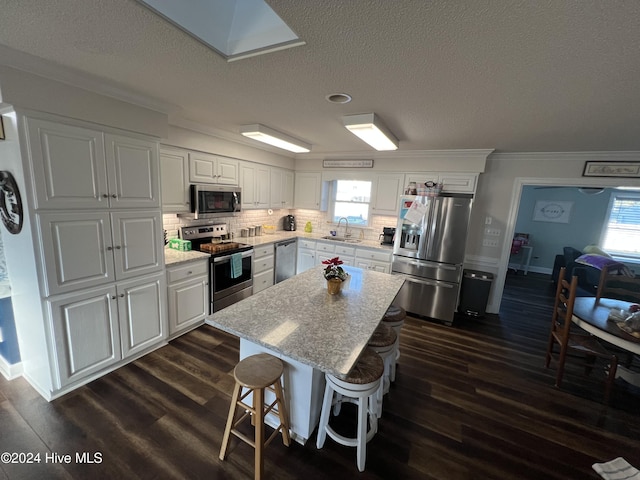 kitchen featuring white cabinets, appliances with stainless steel finishes, a kitchen breakfast bar, and sink