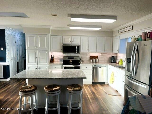 kitchen with a center island, light stone countertops, white cabinetry, and stainless steel appliances