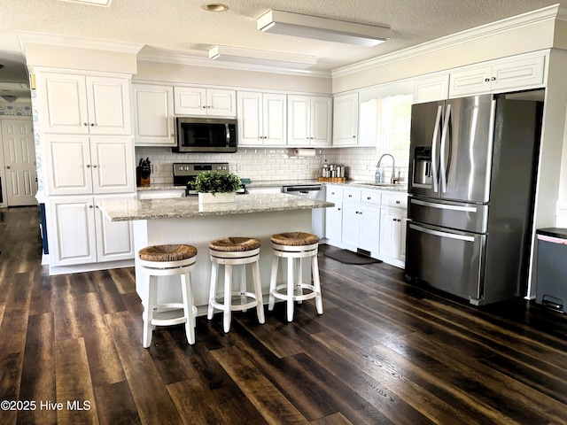 117 Buds Ln, Cedar Point, NC 28584 - kitchen featuring appliances with stainless steel finishes, crown molding, white cabinetry, a center island, and a textured ceiling