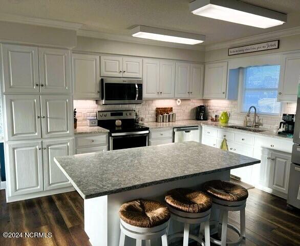 kitchen with white cabinets, sink, a kitchen island, and stainless steel appliances