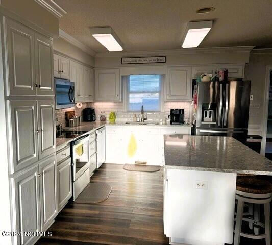 kitchen with white cabinets, a kitchen island, sink, and appliances with stainless steel finishes