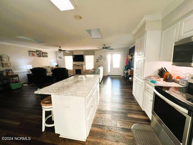 kitchen featuring a kitchen island, a kitchen bar, white cabinetry, and stainless steel appliances