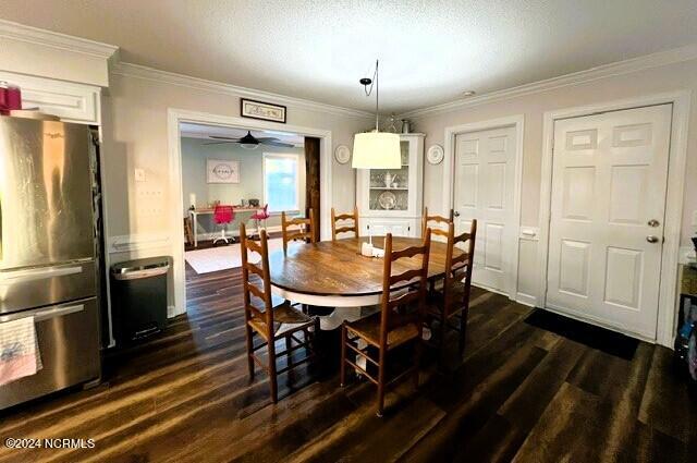 dining room featuring crown molding, ceiling fan, dark wood-type flooring, and a textured ceiling