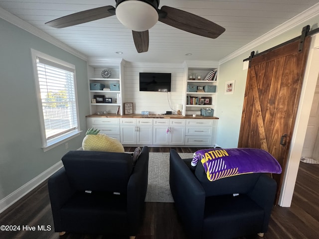 living room with built in shelves, ceiling fan, a barn door, dark hardwood / wood-style floors, and ornamental molding